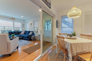 Un salon moderne avec un canapé bleu, un fauteuil blanc et un coin repas comprenant une table et des chaises.