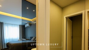 A modern hotel room with a bed, a seating area, and a mirror.