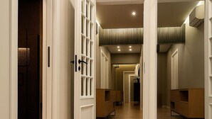 A hallway with wooden flooring, white walls, and a mirrored wall on the right.