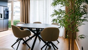 A modern dining area with a round table, four chairs, and a large potted plant.
