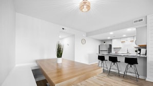 Una cocina moderna con armarios blancos, una mesa de comedor de madera y taburetes negros.