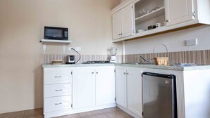 Eine Küche mit weißen Schränken, einer Mikrowelle, einem Mixer und einem Kühlschrank.