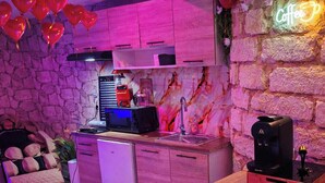 A cozy kitchen with a stone wall, a coffee machine, and a red coffee machine on the counter. - Spa Suite la caverne Private terrace (Montpellier)