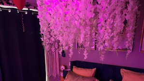 A bedroom with a large bed, decorative pillows, and a wall-mounted floral arrangement. - Spa Suite la caverne Private terrace (Montpellier)
