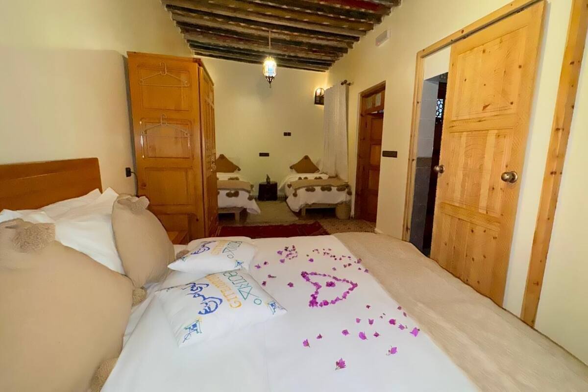 A hotel room with a bed, wooden wardrobe, and a small bathroom visible through an open door.