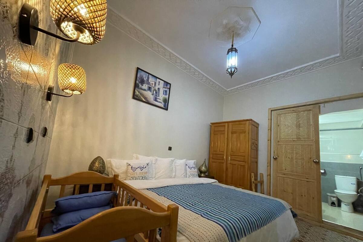 A bedroom with a bed, wooden wardrobe, and a small wooden chair.