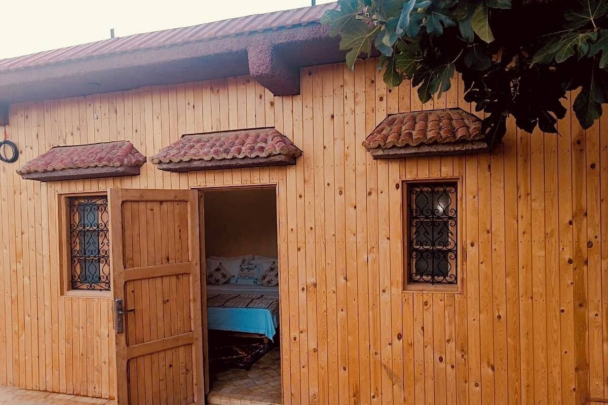 A wooden building with a tiled roof, a door, and two windows.