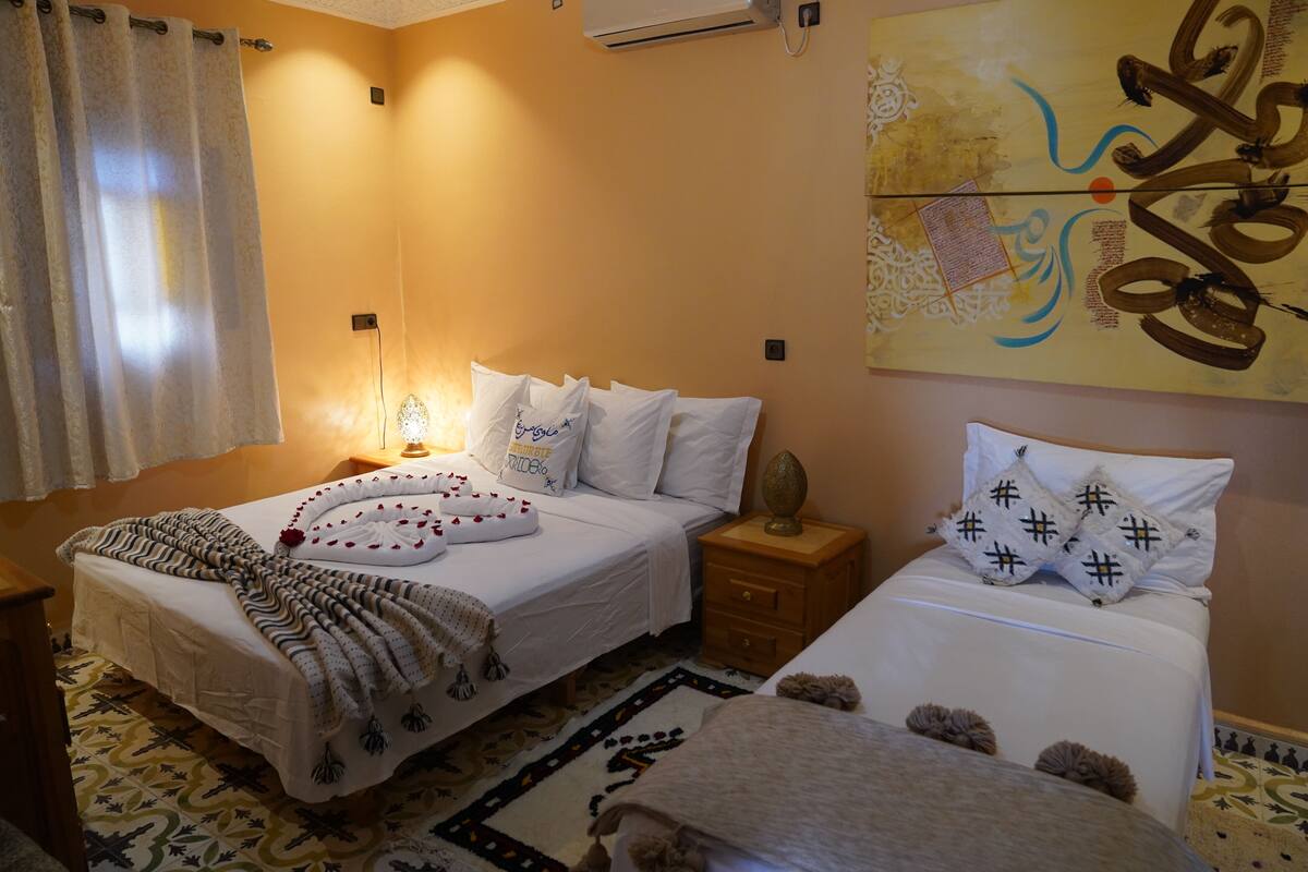 A hotel room with a bed, bedside tables, a lamp, a rug, and a wall decoration.