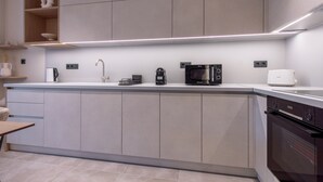 Una cucina moderna con mobili grigi, un piano di lavoro bianco e un forno a incasso.