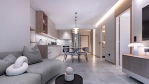 Un soggiorno moderno con un divano grigio, un tavolo da pranzo con sedie e un tavolino nero con un oggetto decorativo.