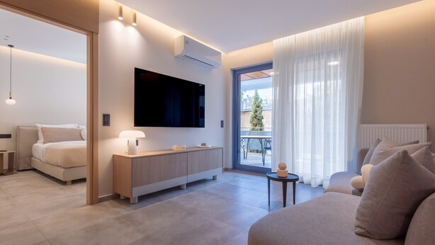Una moderna camera d'albergo con un letto, una poltrona, una TV, un tavolino e un balcone con vista.