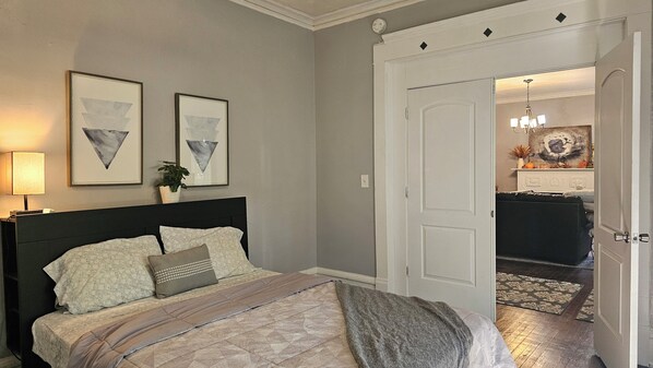 A bedroom with a bed, a nightstand, and a wall-mounted lamp.