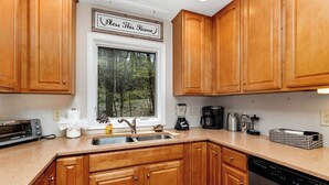 A kitchen with wooden cabinets, a double sink, a toaster, a coffee maker, and a dishwasher.