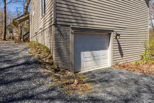 Une maison avec un portail de garage, des fondations en pierre et une allée gravillonnée.