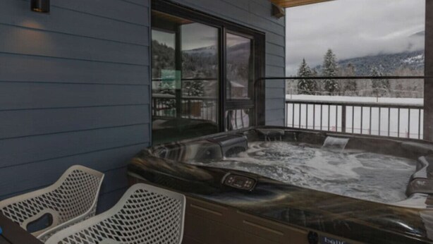 Ein Whirlpool auf einem Balkon mit Blick auf verschneite Berge.