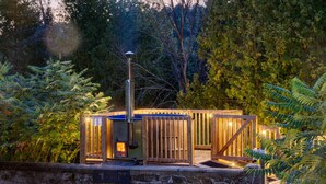 Een houten constructie buiten, met een fundering van steen, omringd door weelderige begroeiing en bomen.