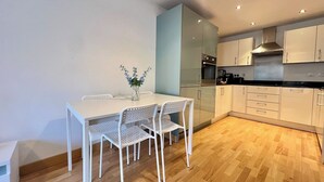 Una cocina moderna con armarios blancos, una mesa de comedor con sillas y un florero con flores.