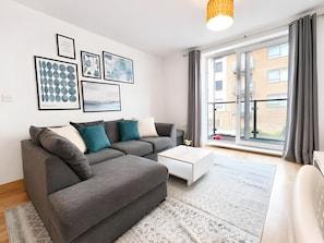 A modern living room with a grey sectional sofa, a white coffee table, and artwork on the wall.
