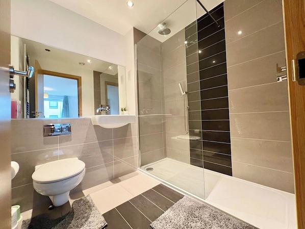 A modern bathroom with a toilet, sink, and glass-enclosed shower area.