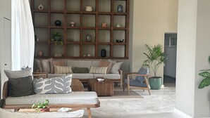 Una sala moderna con un sofá seccional, una mesa de centro de madera y una estantería empotrada con objetos decorativos.