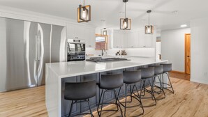 A modern kitchen with a large island, stainless steel appliances, and bar stools. - Charming 4 bedroom, 3 bathroom Brick Home located on 3 rural acres. (Colton)