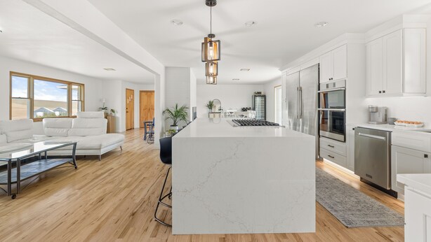 A modern kitchen with white cabinetry, a marble island, stainless steel appliances, and a pendant light. - Charming 4 bedroom, 3 bathroom Brick Home located on 3 rural acres. (Colton)