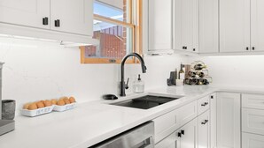 A modern kitchen with white cabinets, a black faucet, and a wine rack. - Charming 4 bedroom, 3 bathroom Brick Home located on 3 rural acres. (Colton)