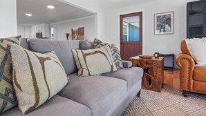 A living room with a grey sofa, a brown leather armchair, and a wooden coffee table.
