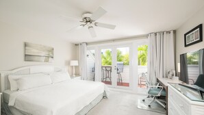Un dormitorio con cama, escritorio, silla, ventilador de techo y vista al exterior.