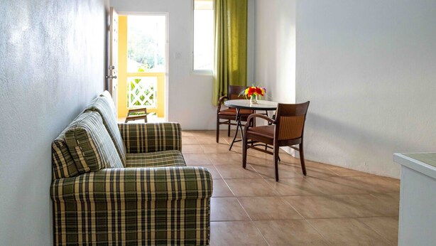 Una habitación con un conjunto de sofás, una mesa de comedor con sillas y vistas a través de una puerta.