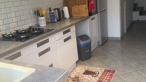 Una cocina moderna con armarios blancos, estufa a gas, refrigerador y basurero.