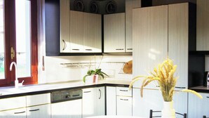 Una cocina moderna con armarios blancos, lavavajillas y una mesa de comedor con sillas.