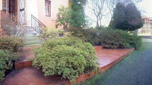 Un edificio con un camino de ladrillo rojo, una reja metálica y una escalera que lleva a una puerta.
