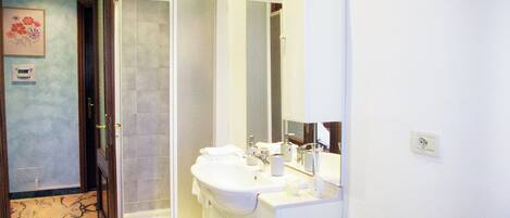 A bathroom with a shower, a sink, and a mirror.