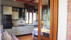 Una cocina con armarios blancos, una estufa y un comedor con mesa y sillas.