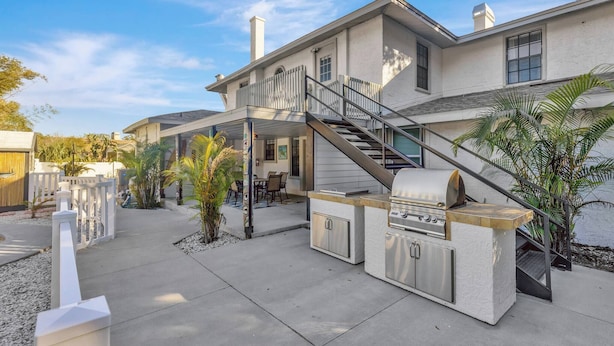 A house with a patio, outdoor grill, and staircase leading to a second floor. - Huge 8BR w/HTD Pool, Ensuites, Games, Near Beach (Palm Harbor)