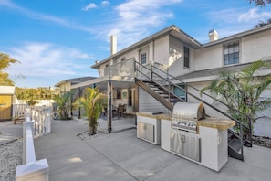 A house with a patio, outdoor grill, and staircase leading to a second floor. - Huge 8BR w/HTD Pool, Ensuites, Games, Near Beach (Palm Harbor)