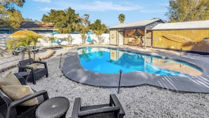 A swimming pool with lounge chairs and a covered area with a wooden deck. - Huge 8BR w/HTD Pool, Ensuites, Games, Near Beach (Palm Harbor)