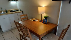 Un petit coin repas avec une table en bois et quatre chaises, une lampe et un paquet de chips.