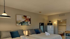 Une chambre d’hôtel avec deux lits, une grande peinture abstraite, un réfrigérateur, une table de chevet et un placard.