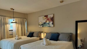Une chambre d’hôtel avec deux lits, un ventilateur de plafond, un tableau et un grand miroir.