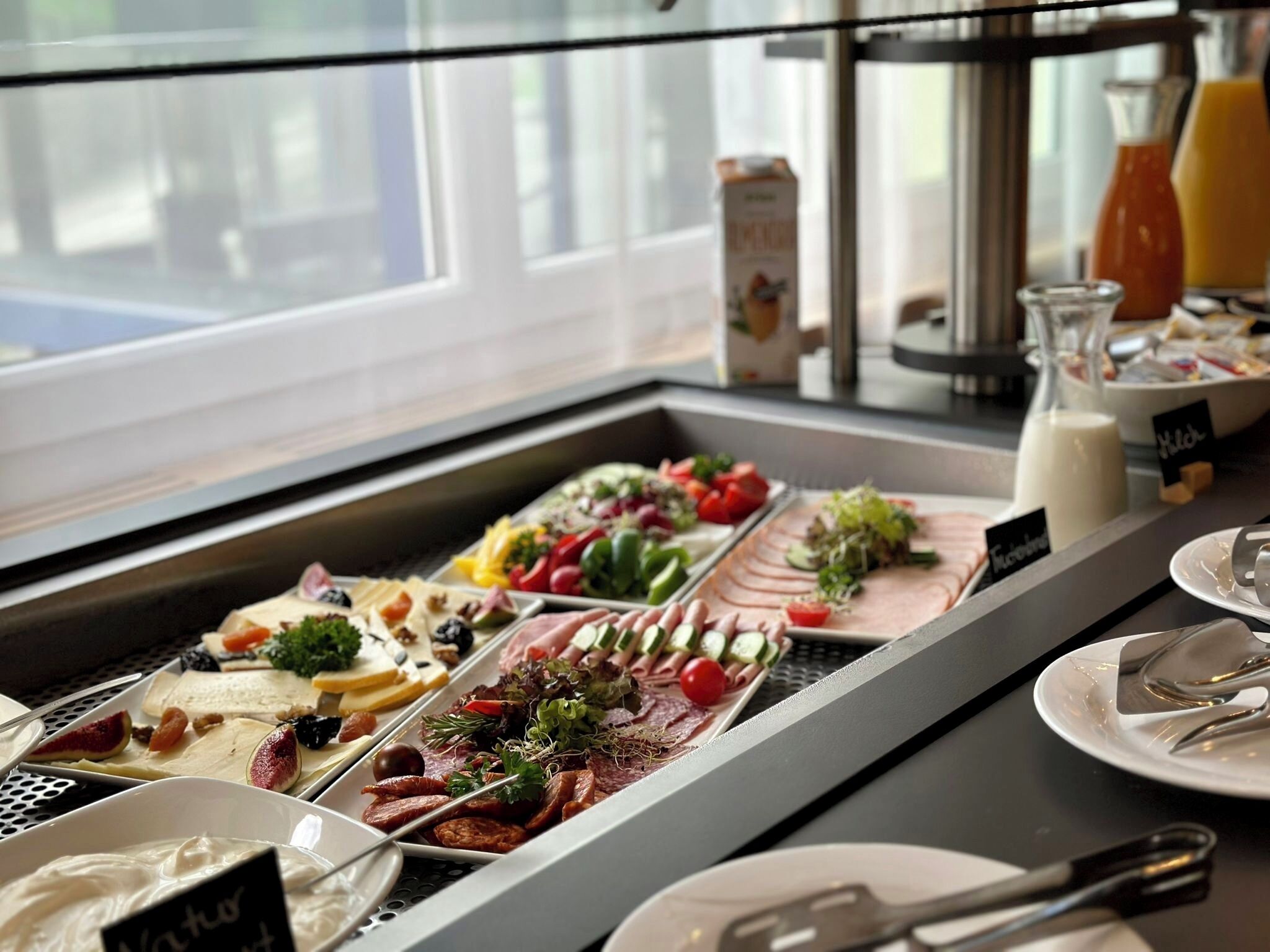 A buffet with various food options including meats, cheeses, and vegetables.