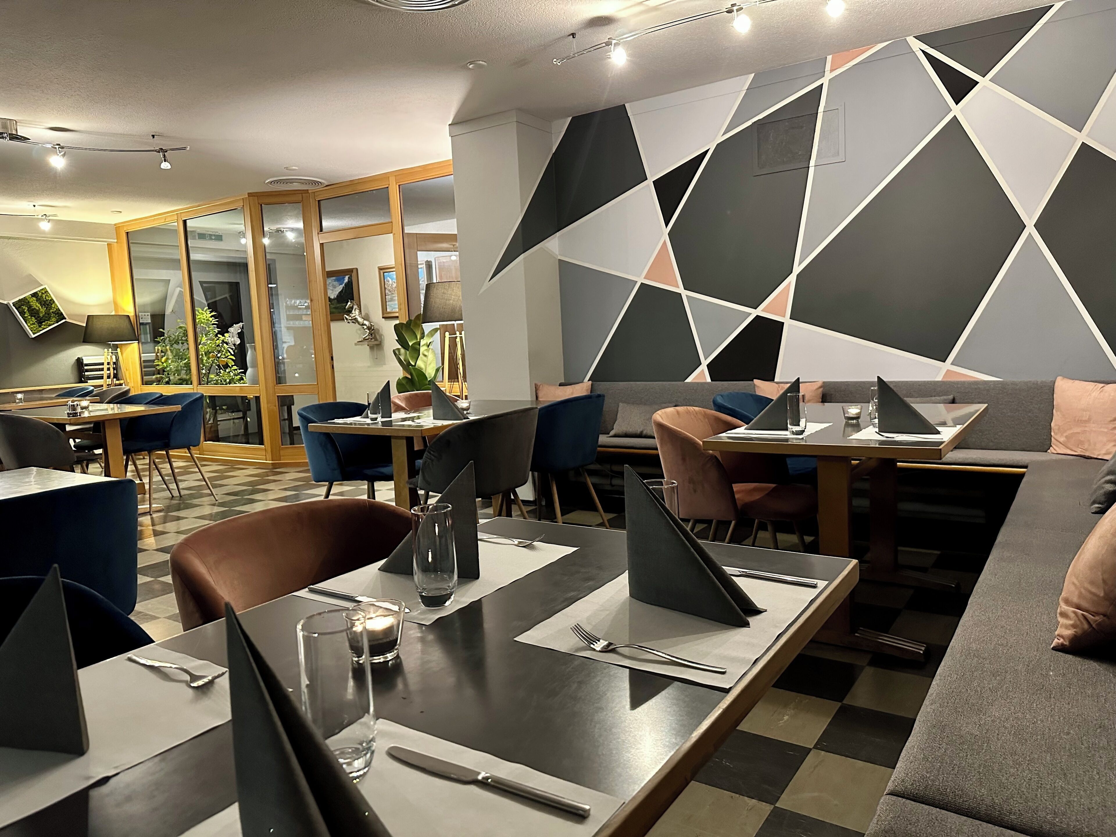 A modern dining area with tables, chairs, and a sofa. There are laptops on the tables, suggesting a work-friendly environment.