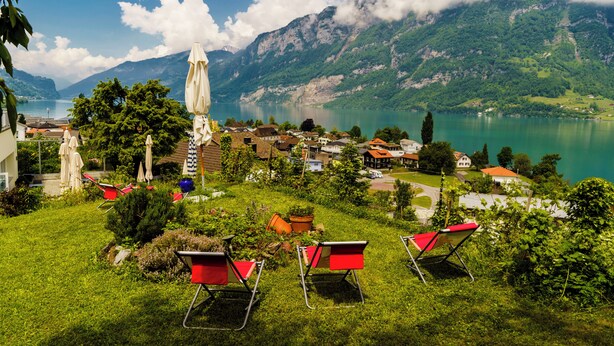 A hillside view of a lakeside village with outdoor seating and a mountain backdrop. - Seeblick Hotel und Restaurant Rössli (Quarten)