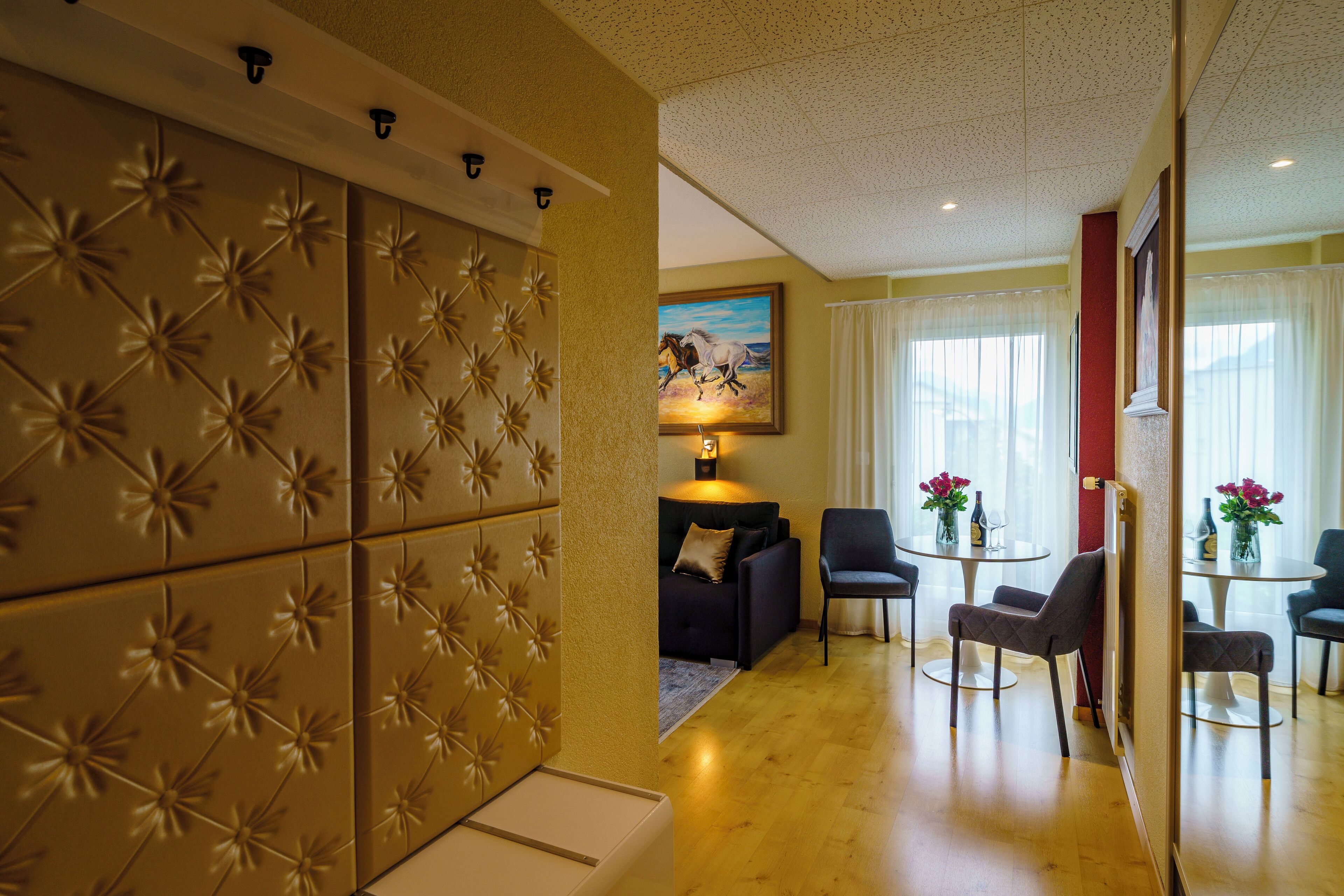 Een moderne woonkamer met een bank, stoelen, een salontafel en een schilderij aan de muur.