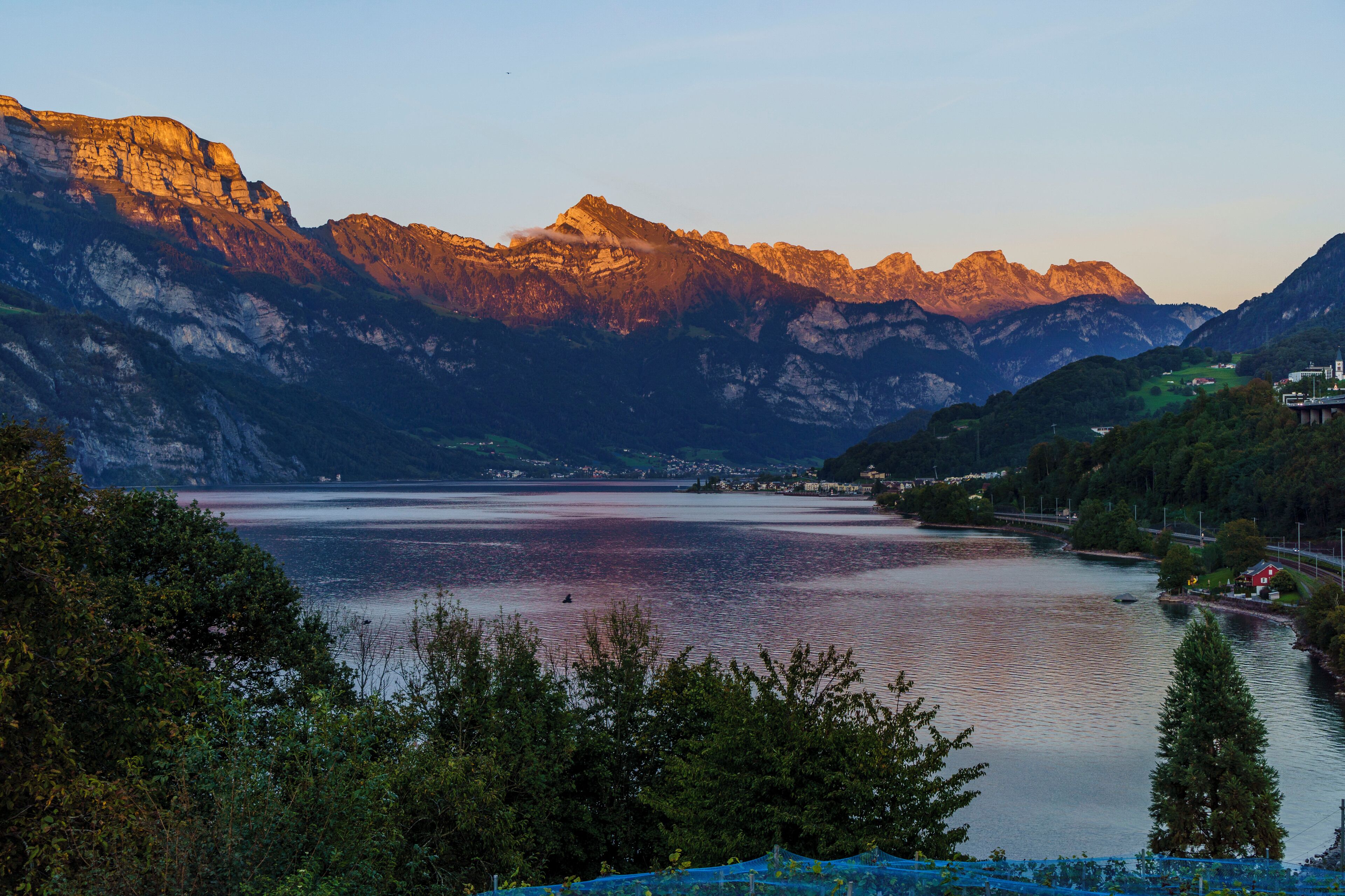 Un paysage montagneux avec un lac, un pont et un petit village.