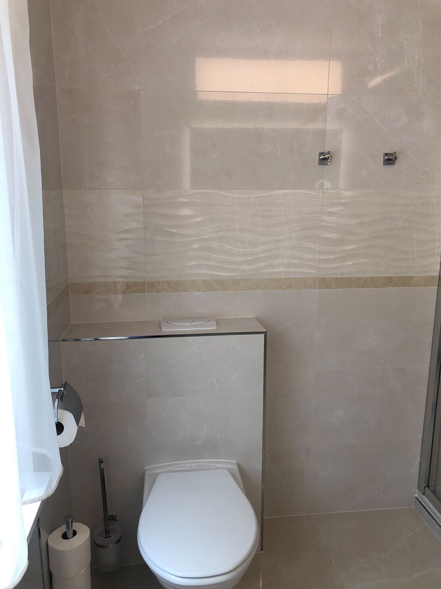 Une salle de bain moderne équipée de toilettes, d’un sèche-mains et d’un porte-rouleau de papier toilette.