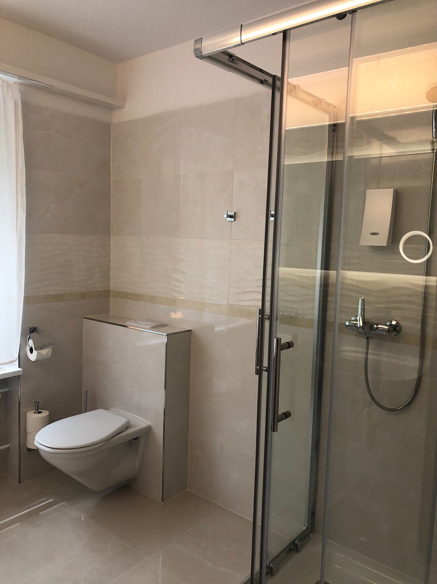 Un baño moderno con cabina de ducha de vidrio, inodoro y lavabo.