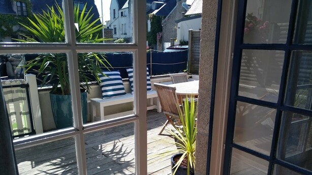 Un espace patio doté d’une terrasse en bois, de meubles d’extérieur et de plantes en pot.