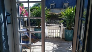 Une terrasse en bois avec une clôture blanche, des plantes en pot et une chaise.